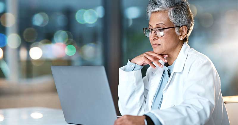 Doctor wearing glasses seeing laptop